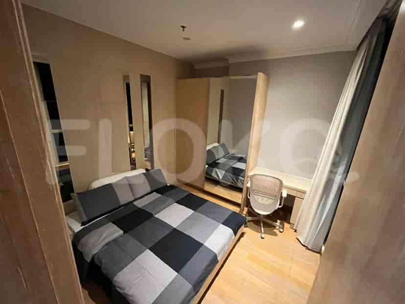 A bedroom featuring a bed with grey and black checkered bedding, a wardrobe with mirrors, and a study desk.