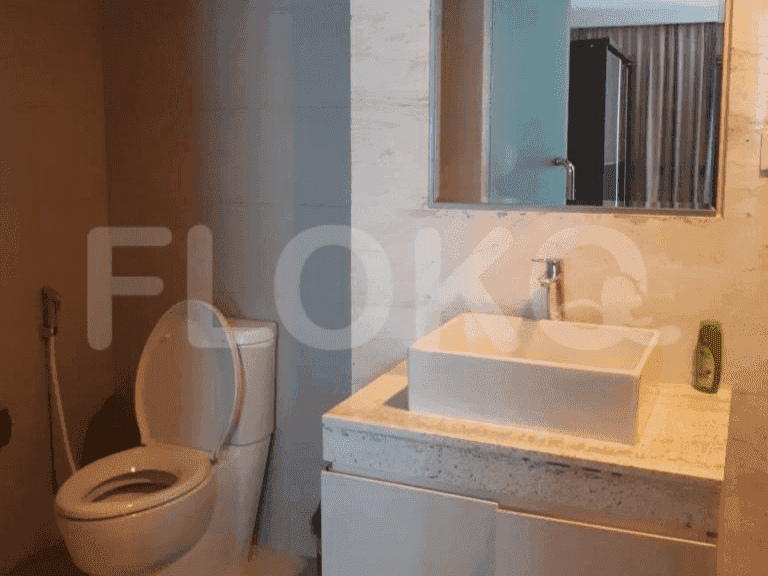 A contemporary bathroom with a white toilet, sink, and a light-colored marble wall.