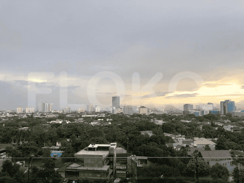 Aerial view of a city with buildings, trees, and a cloudy sky.