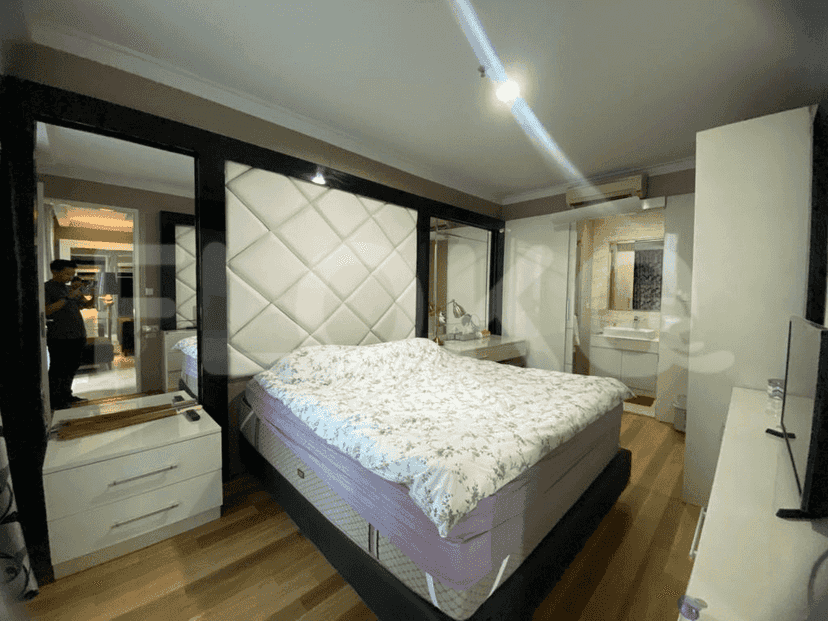 A luxurious bedroom featuring a large bed with a tufted headboard and mirrored accents.