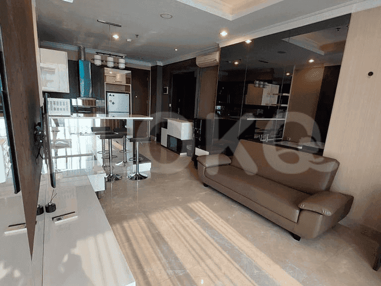Living area with a sofa, TV, and an adjacent kitchen and dining space.
