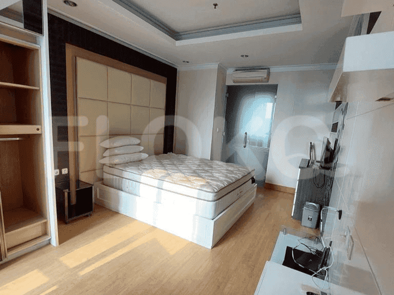 Well-lit bedroom with a queen-sized bed, headboard, and wardrobe.