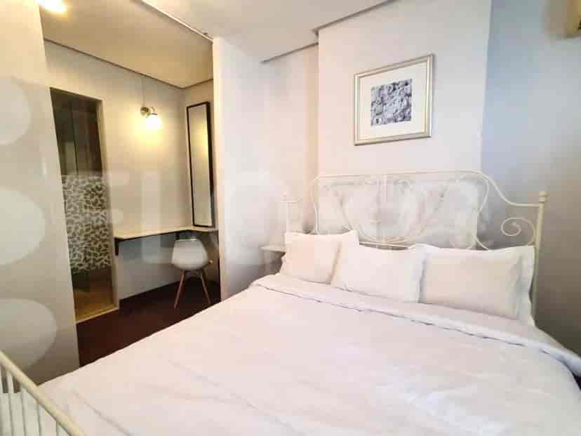 A bedroom featuring a white metal bed frame with white bedding and a framed artwork on the wall.