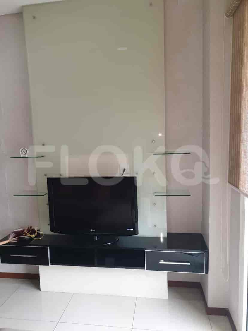 A living room with a TV mounted on a wall and glass shelves.