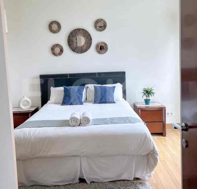 An elegant bedroom with a bed, nightstands, and wall art.