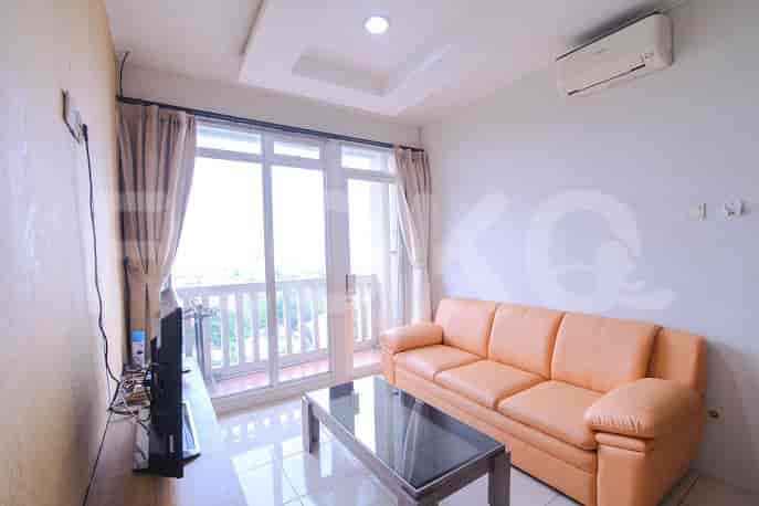 Living room with an orange sofa, glass coffee table, and access to a balcony.