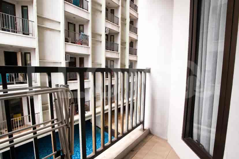A small balcony with a view of the building exterior and a swimming pool.