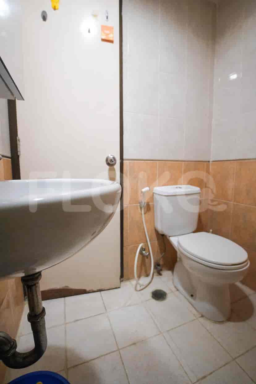 A bathroom with a toilet, sink, and tiled walls.