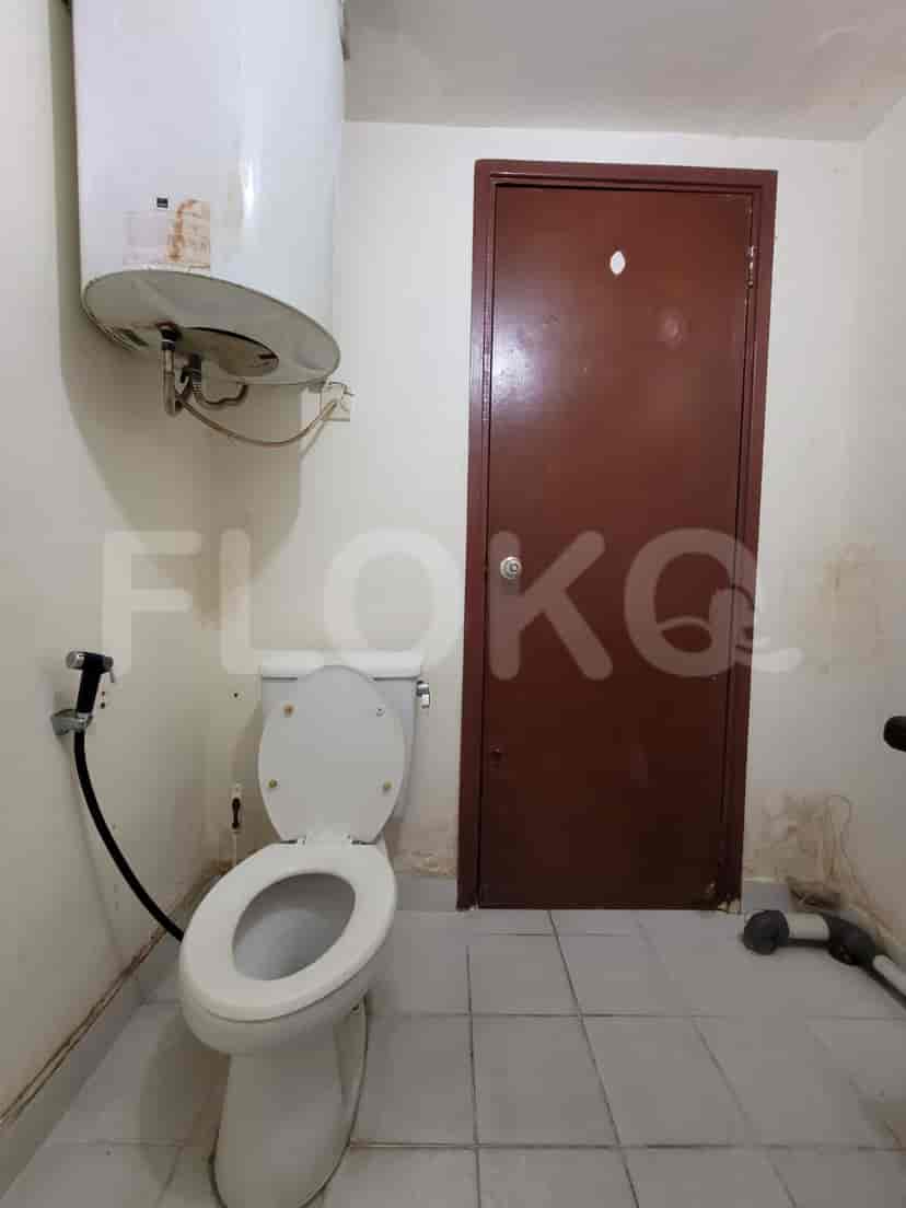 A separate toilet room with a toilet, water heater, and a brown door.