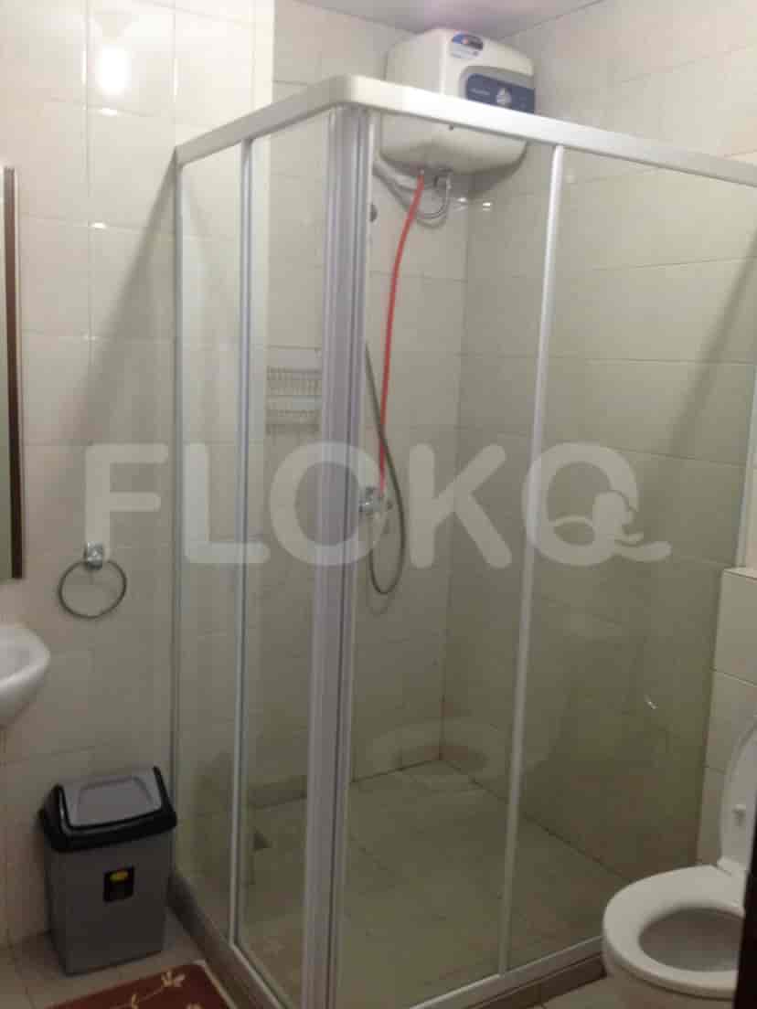 A modern bathroom featuring a glass-enclosed shower, a toilet, and beige tiled walls.