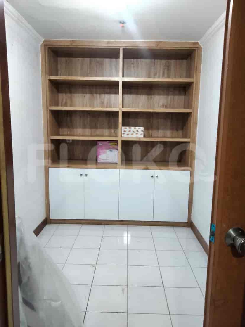 A walk-in closet with wooden shelves and white cabinets.
