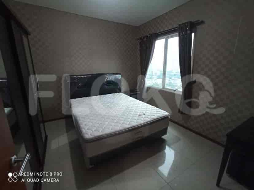 A bedroom with a double bed, wallpapered walls, and a window.