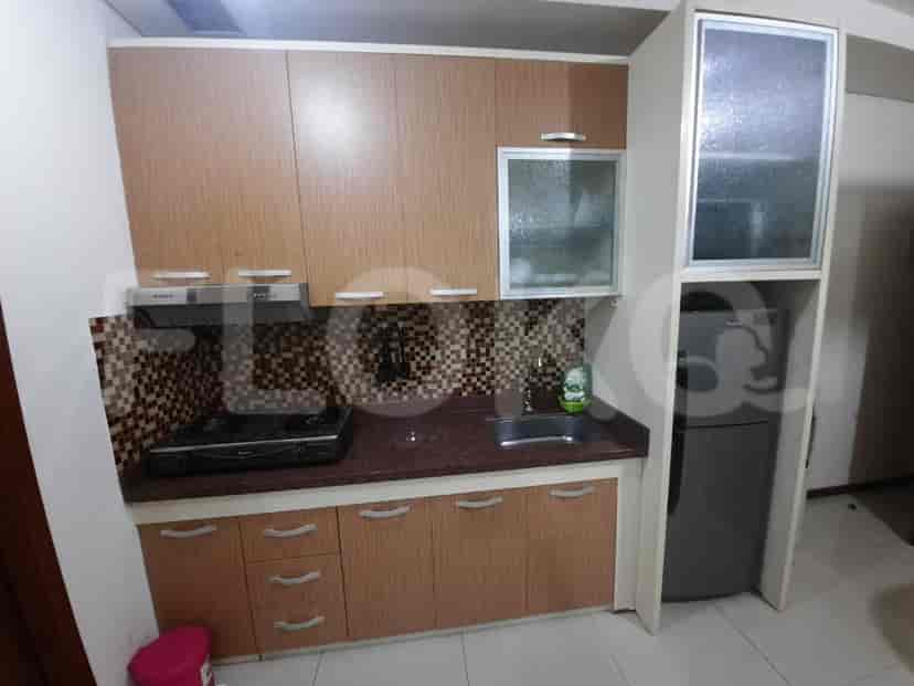 A compact kitchen with wooden cabinets, a gas stove, and a refrigerator.