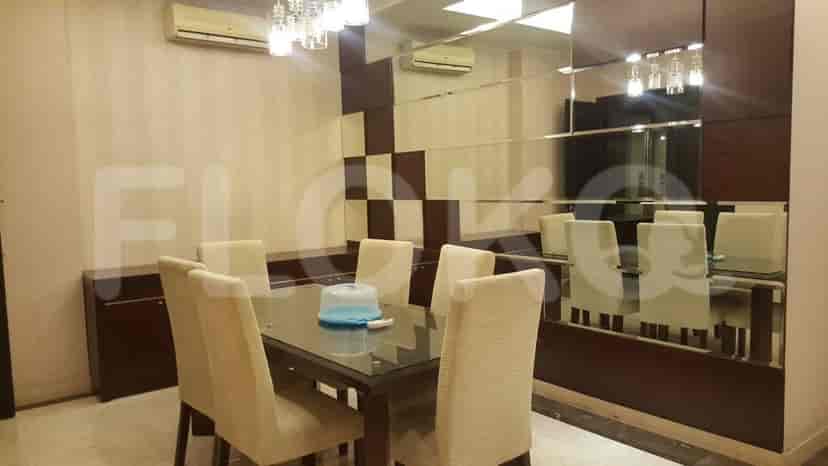 A modern dining room with a glass-topped table and six beige upholstered chairs, featuring a large mirrored wall.