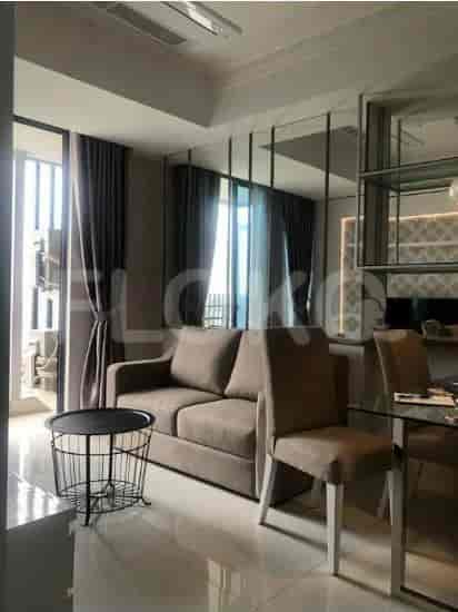 Living room with a sofa, side table, and dining area featuring a clear glass table.