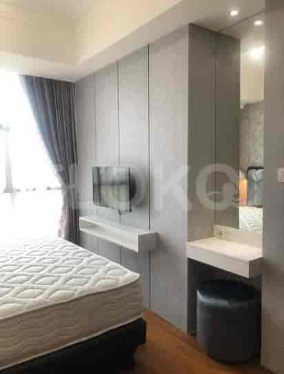 Modern bedroom featuring a bed with a white mattress, a wall-mounted TV, and built-in storage.