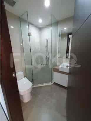 Kamar mandi modern dengan pancuran kaca dan toilet putih.
