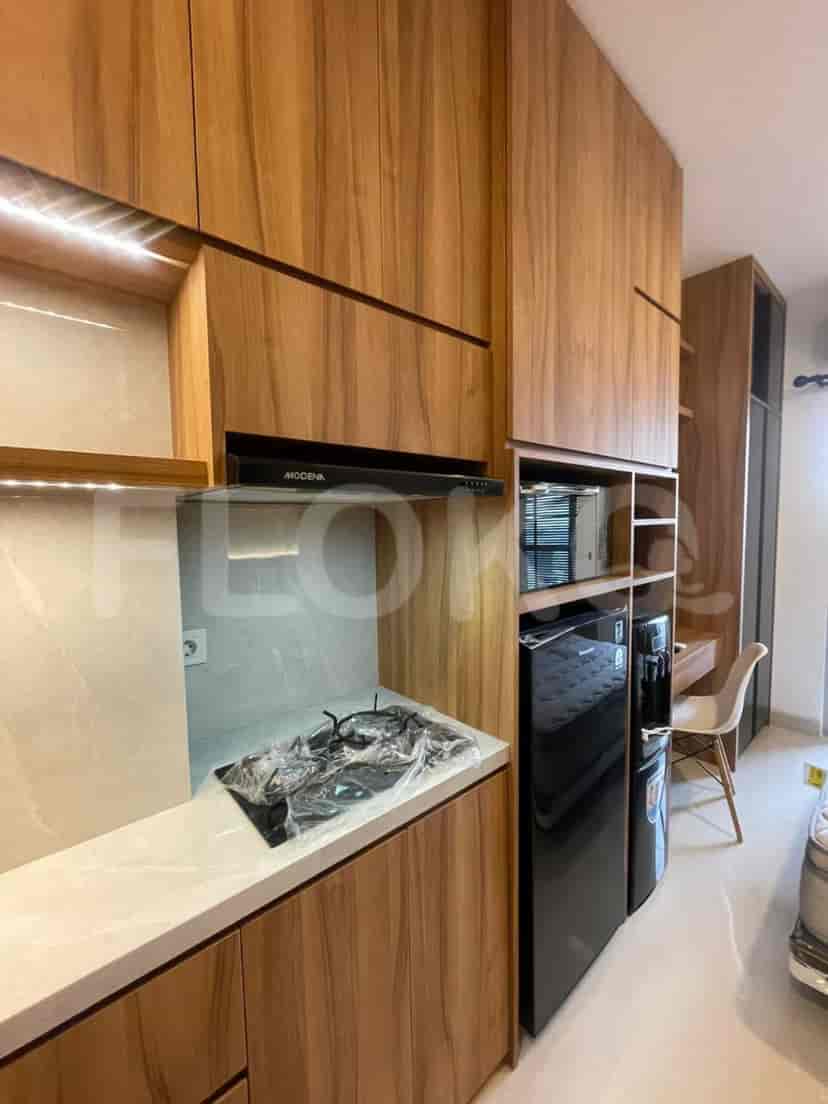 Small kitchen area with wooden cabinets, gas stove, and black appliances.