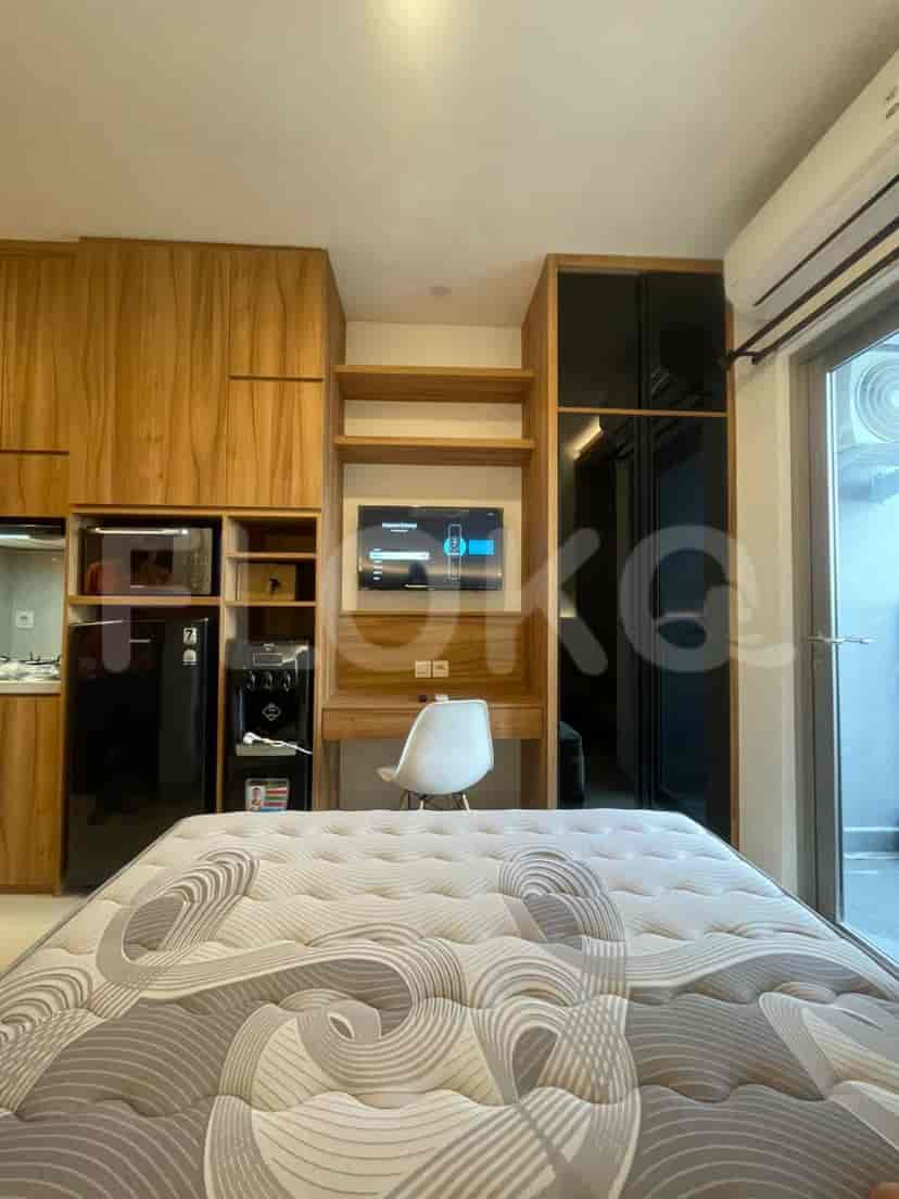Modern studio bedroom with wooden cabinetry, a double bed, and integrated desk.
