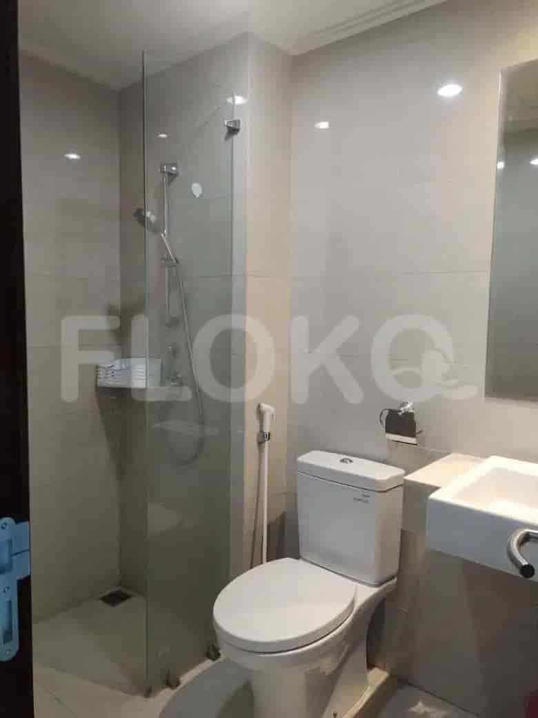 A compact modern bathroom featuring a glass shower, toilet and sink.