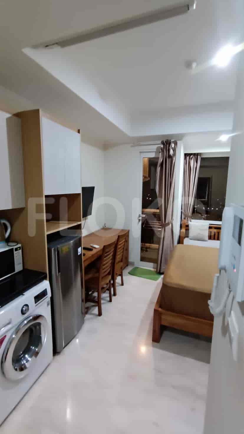 Apartemen kompak dengan area gabungan ruang tamu dan dapur yang menampilkan peralatan penting.