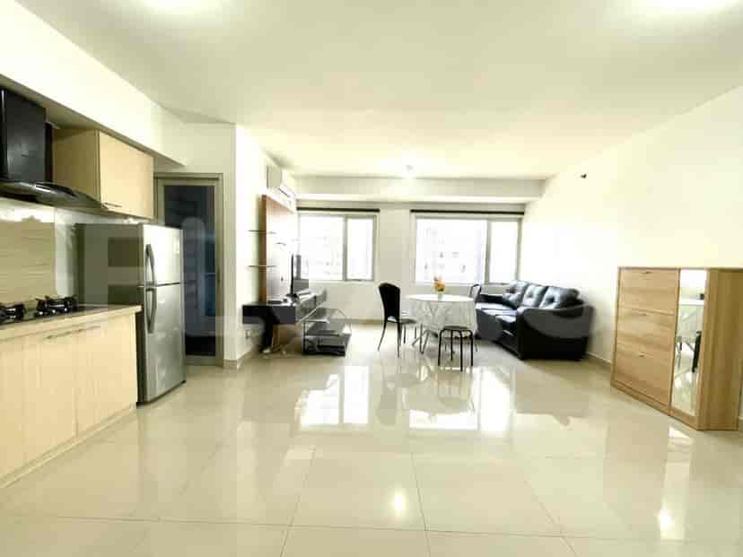 A combined living and kitchen space with a dining table and a black leather sofa.