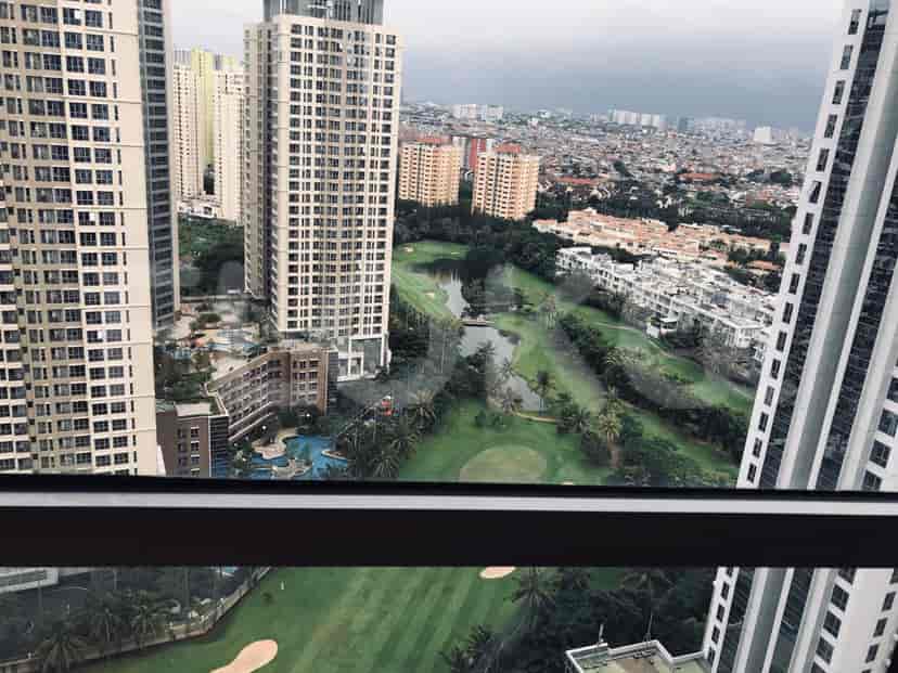 Pemandangan menakjubkan dari jendela apartemen yang menampilkan kota, bangunan, dan lapangan golf.