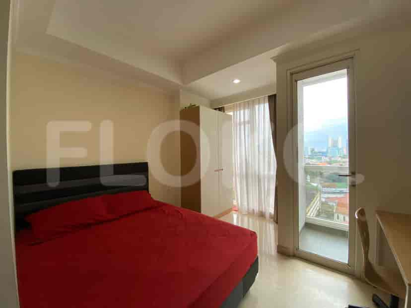 A bedroom with a red bed, a wardrobe, and a balcony view.