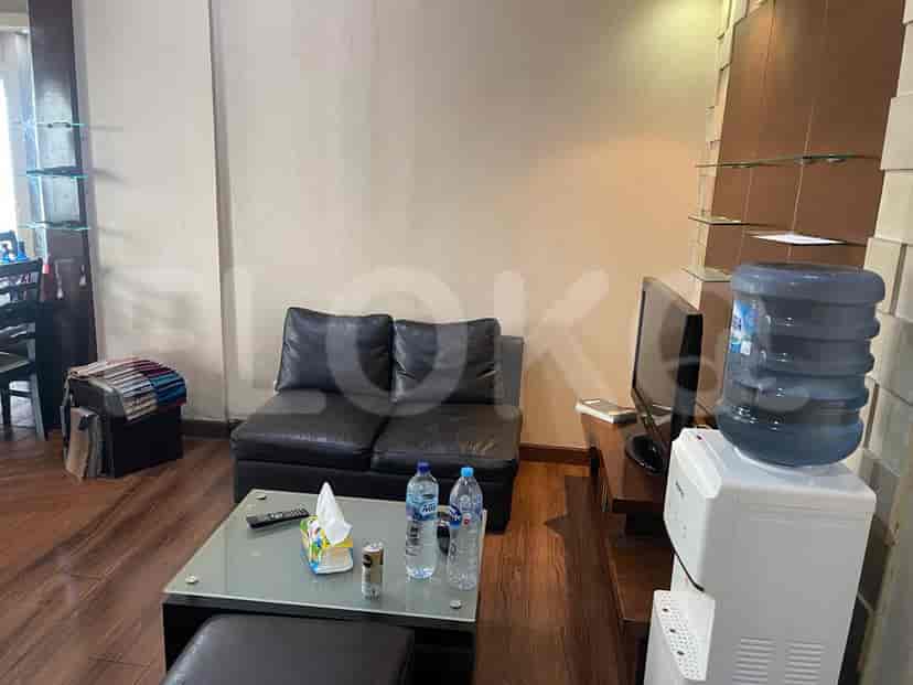 Ruang tamu yang menampilkan sofa kulit hitam, TV, dan meja kopi.