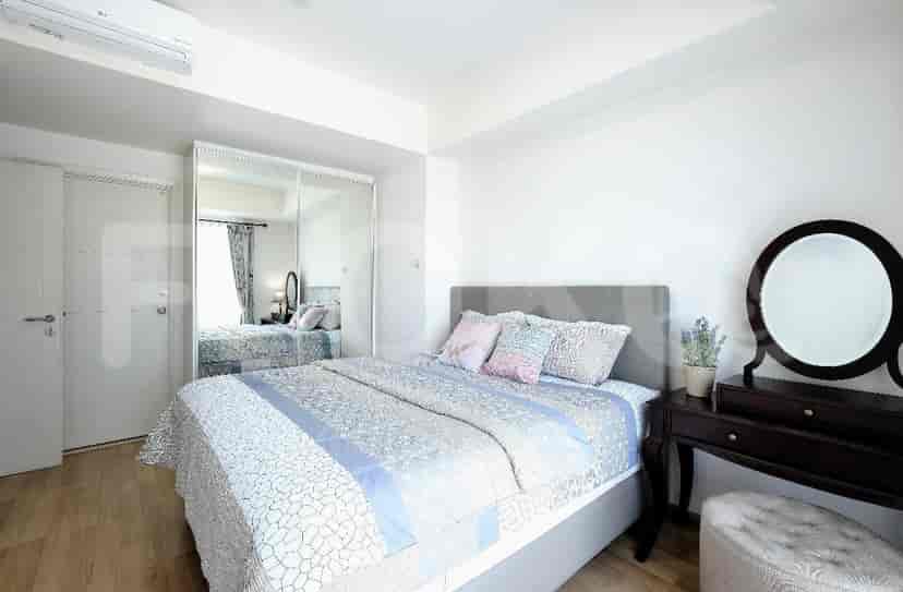Kamar tidur modern yang menampilkan tempat tidur dengan bantal dekoratif, lemari besar, dan meja rias dengan cermin.