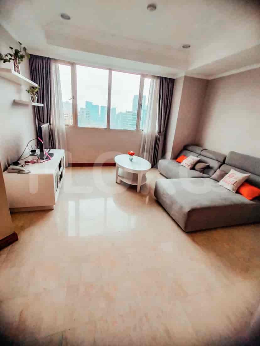 A living room with an L-shaped sofa, TV, and large window.
