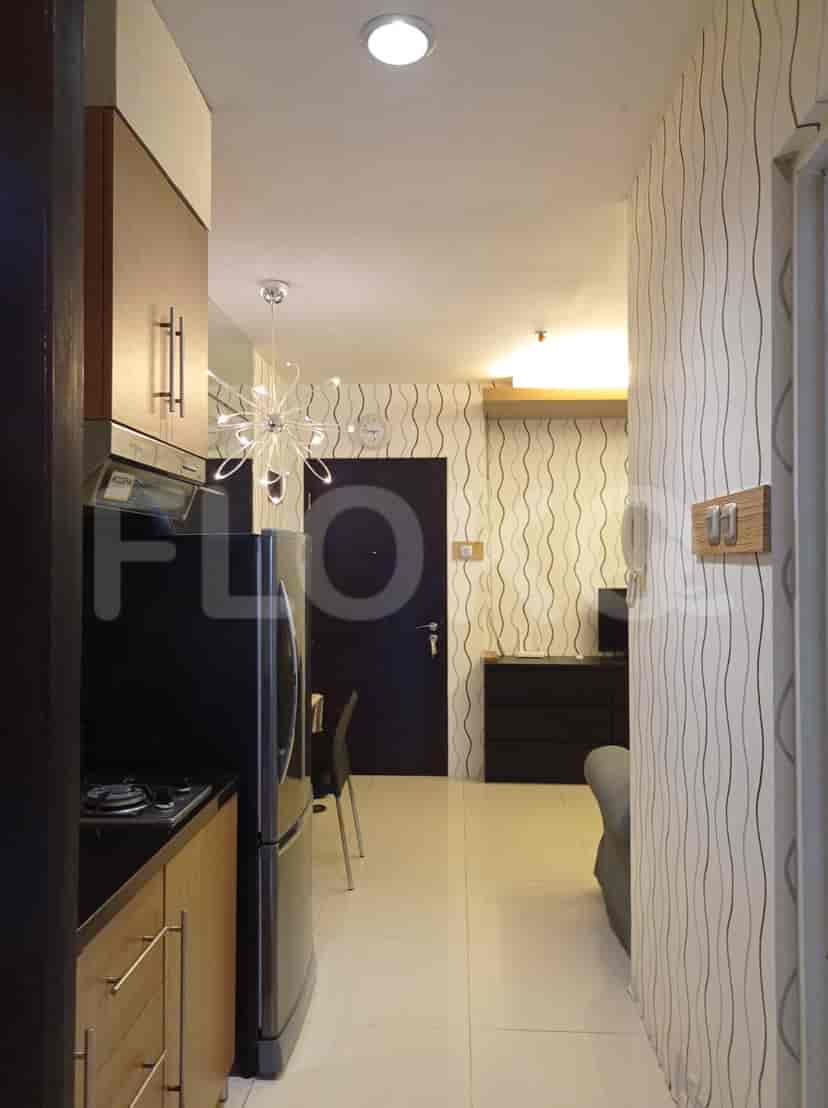 A view of the kitchen area with cabinets, stove, refrigerator, with a corridor visible.