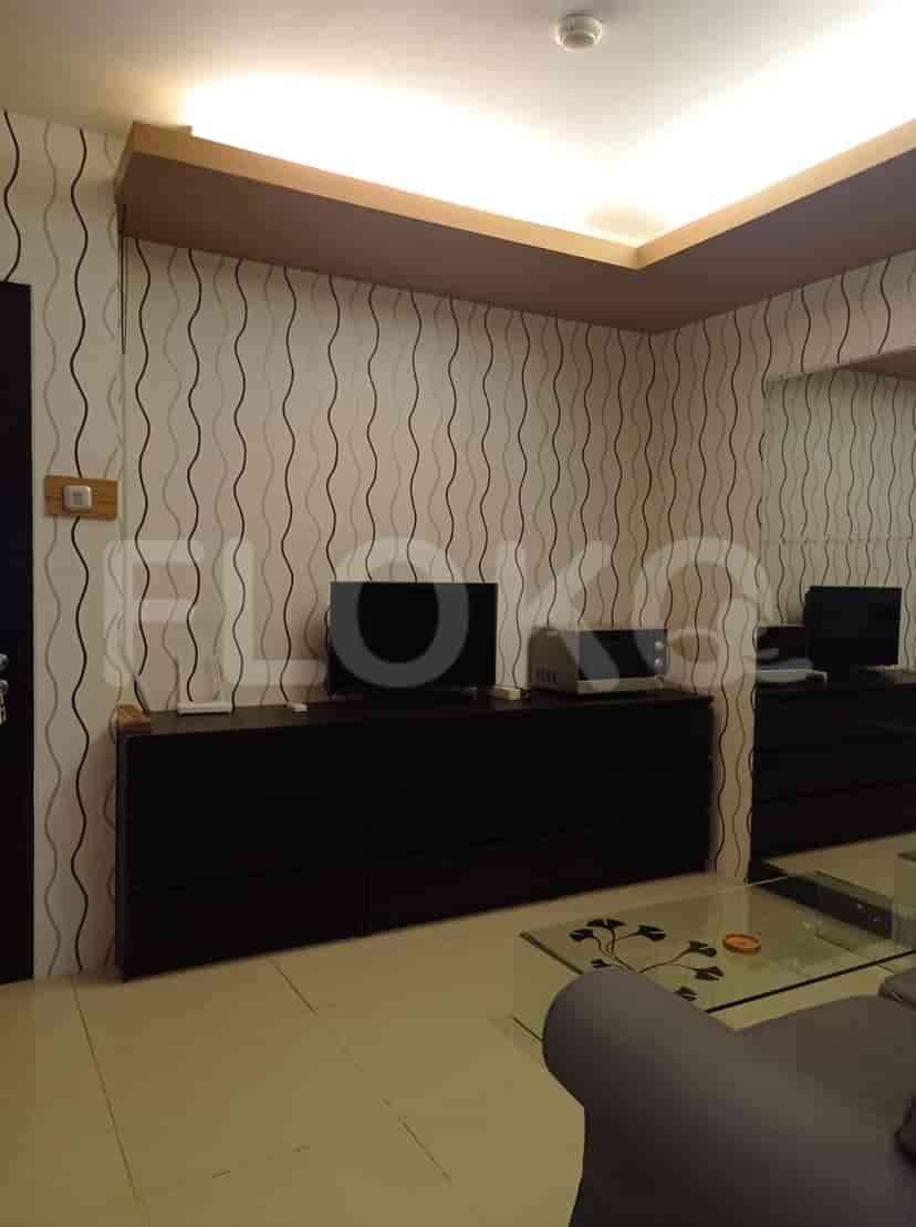 A living room with a TV, storage cabinets, and patterned wallpaper.