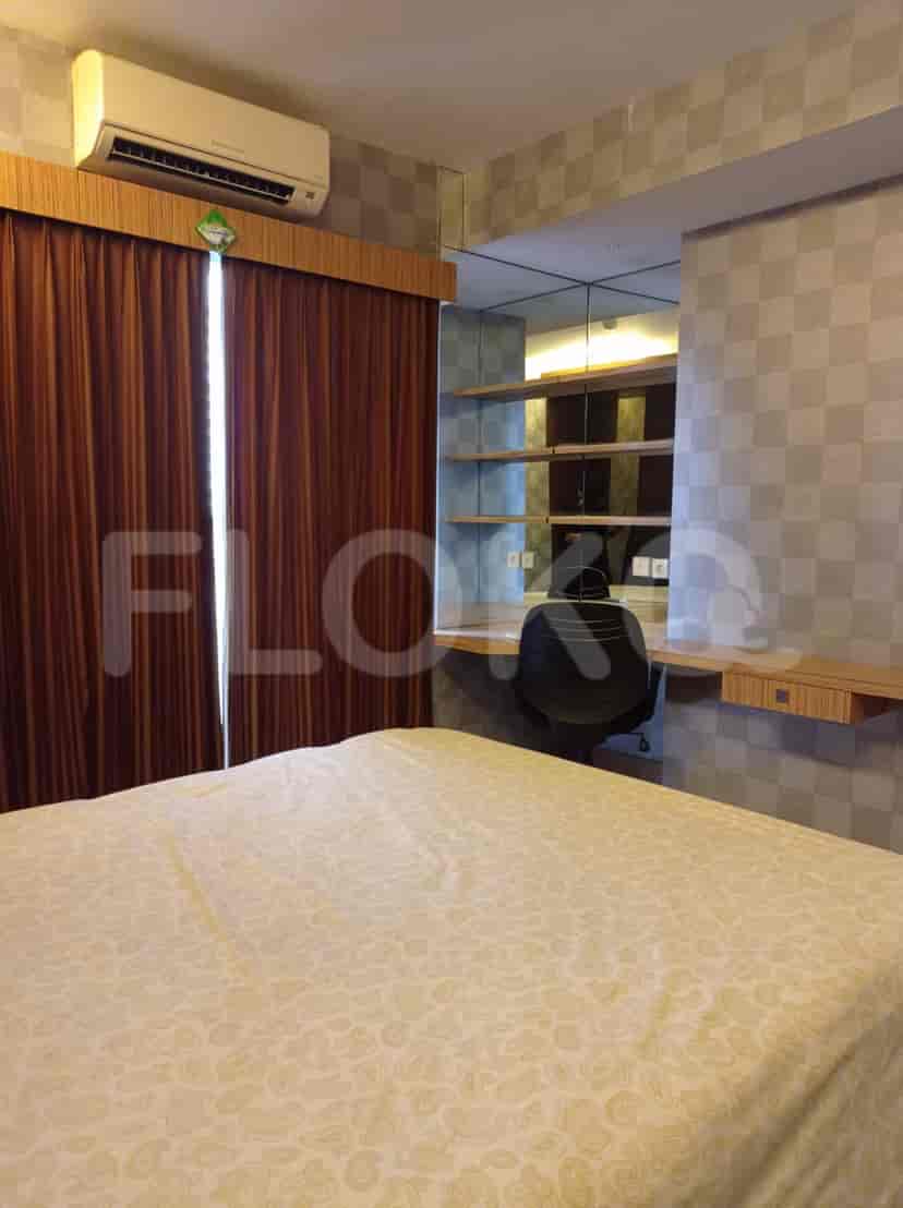 A bedroom with a bed, desk, shelves, curtains, and patterned wallpaper.