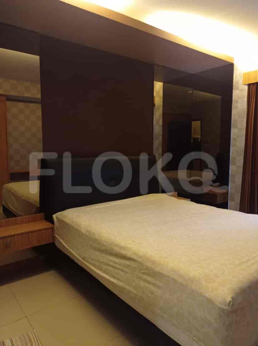 A bedroom with a bed, mirrors, and patterned wallpaper.