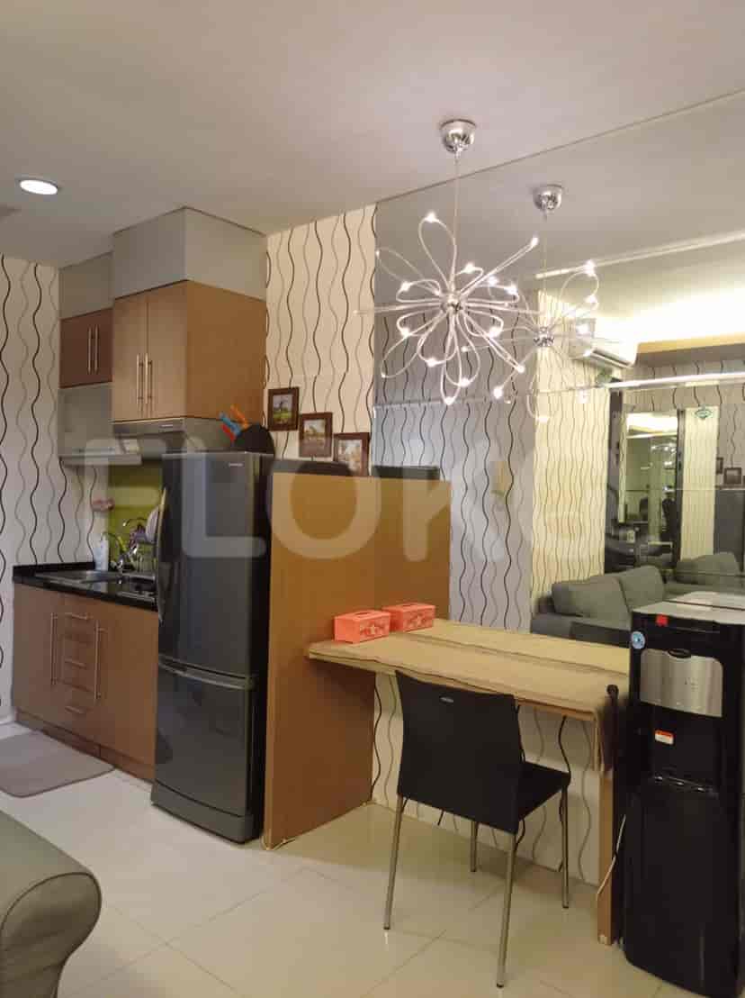 A dining area with a table, chairs, lighting fixtures and a kitchen with a refrigerator.