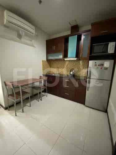 A small kitchen with a refrigerator, cabinets, and a table.