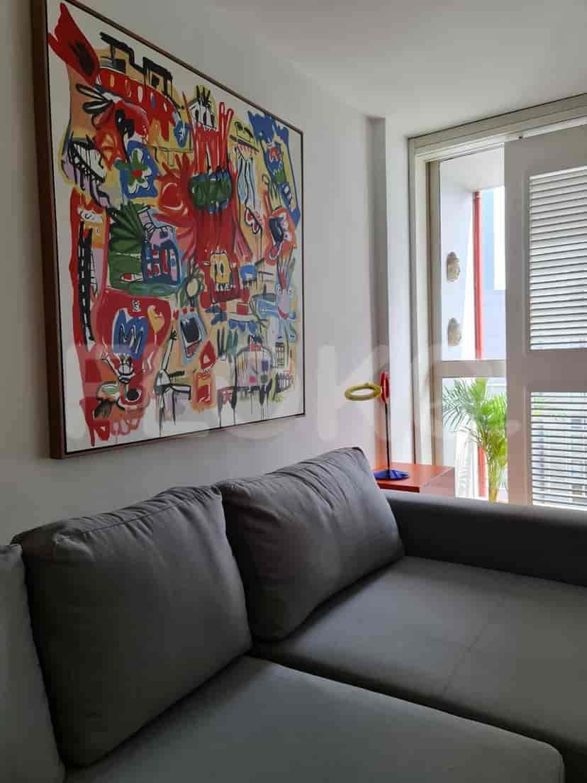 An eye-level view of a large, colorful artwork above a gray sofa.