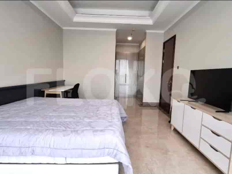 A bedroom with a king-size bed, a desk with a chair, and a TV on a dresser.