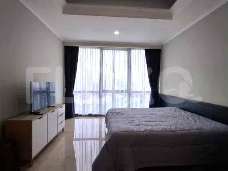 A bedroom featuring a king-size bed, a dresser with a TV, and a large window with curtains.