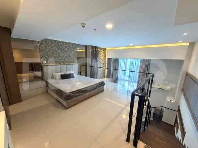 Kamar tidur loteng yang menghadap ke ruang tamu, menampilkan tempat tidur besar dan pagar kaca.