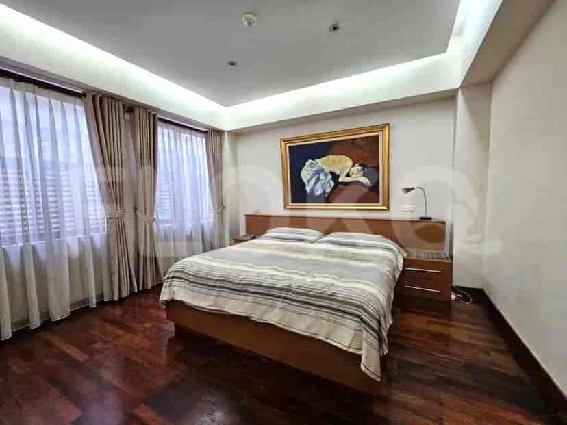 A bedroom with a large bed, bedside tables, and large windows.