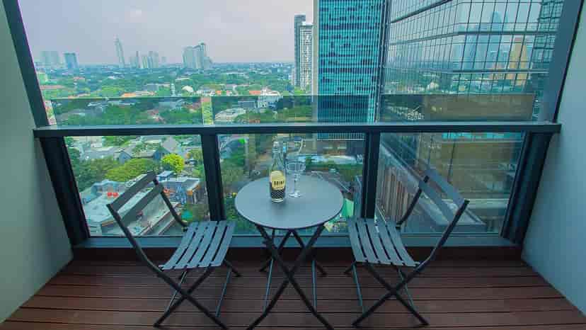 A balcony with a table and chairs and a city view.