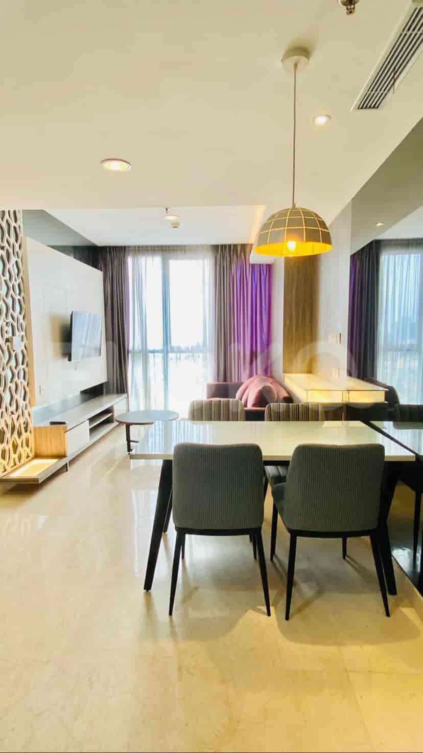 A modern living room with a sofa, dining table, and a large window with sheer curtains.