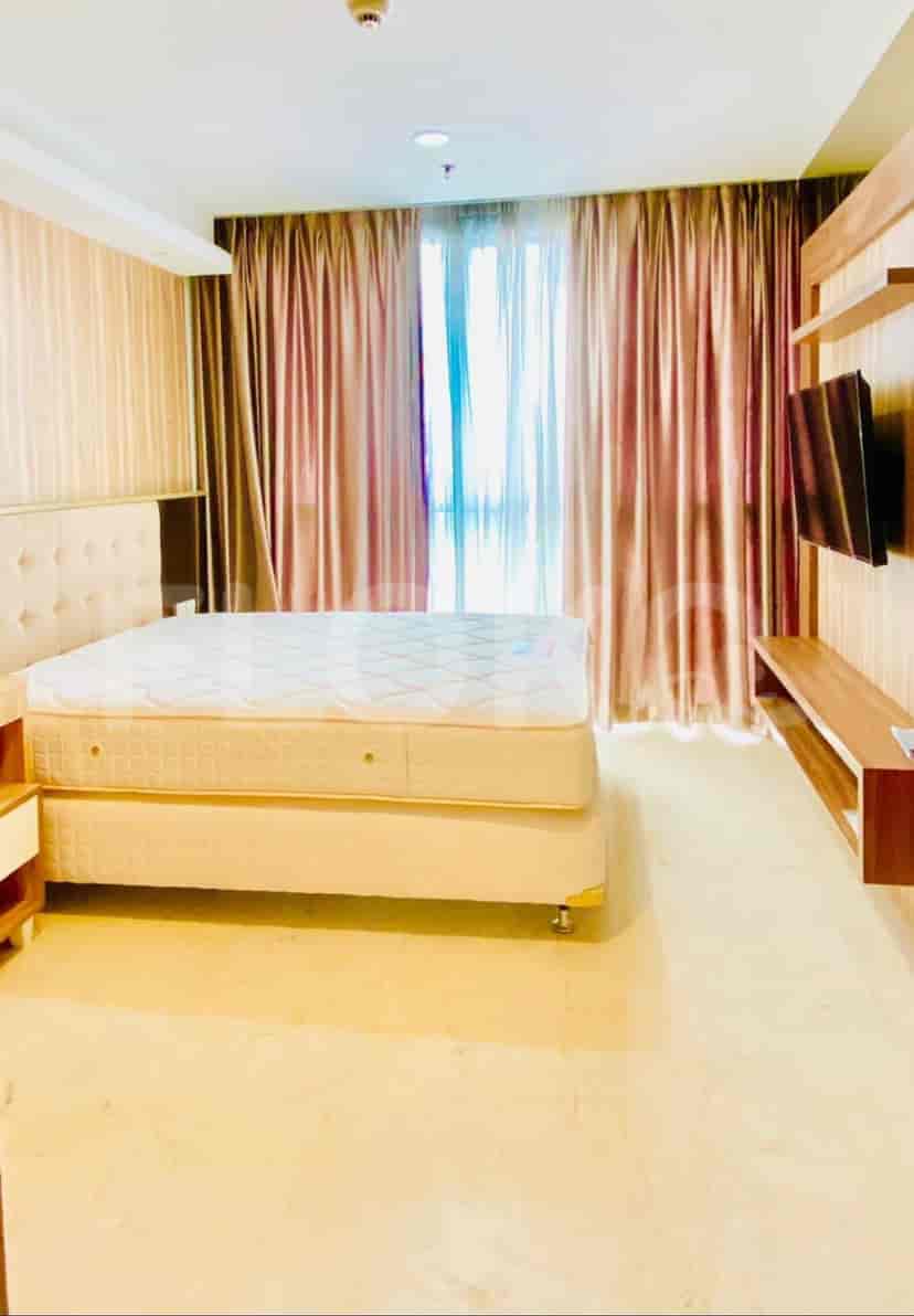 Spacious bedroom with a large bed, sheer curtains, and a view of the city.