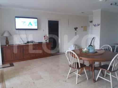 A living room with a dining table, a wooden cabinet, and a TV.