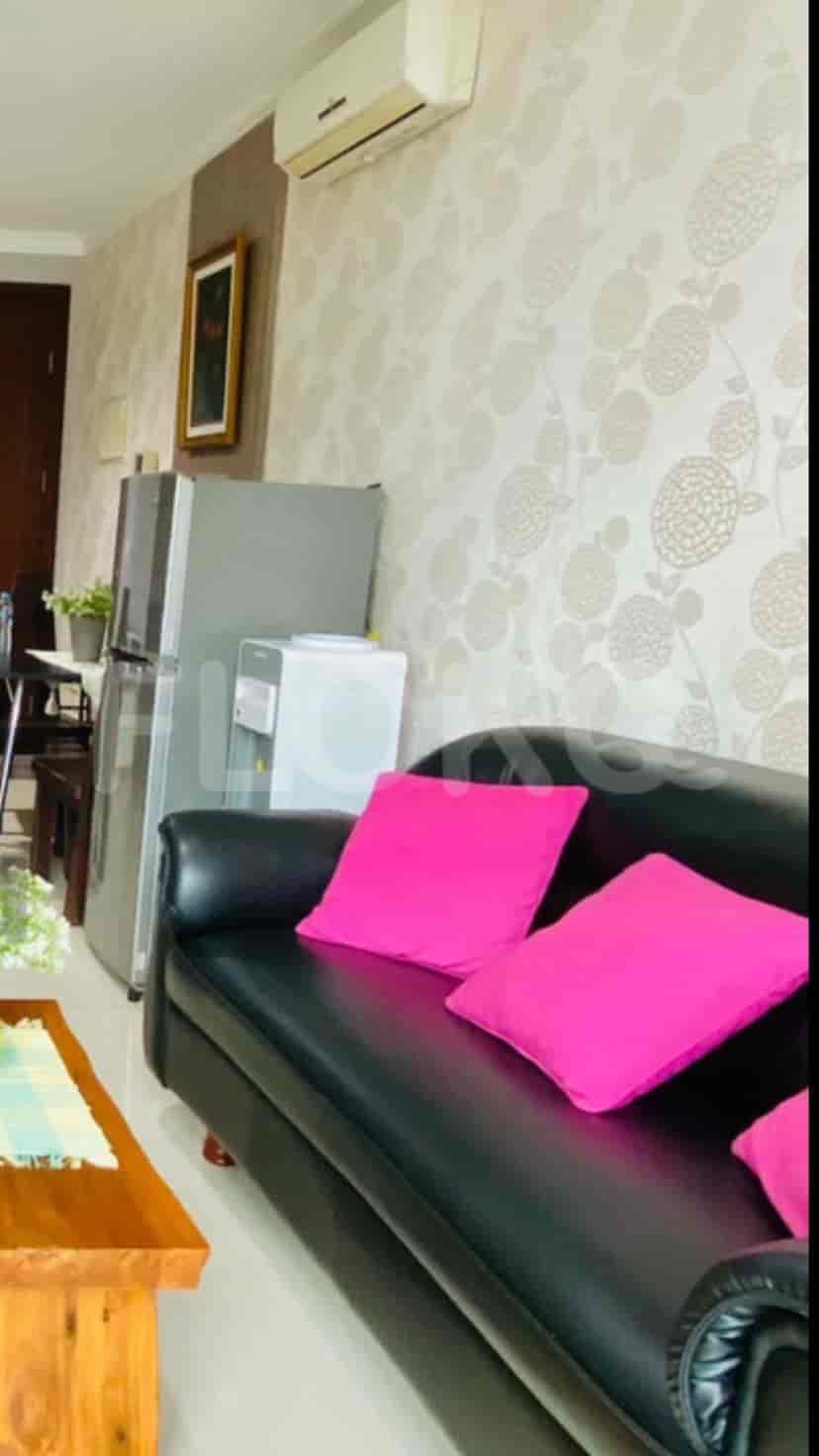 A living room with a black sofa and pink pillows.