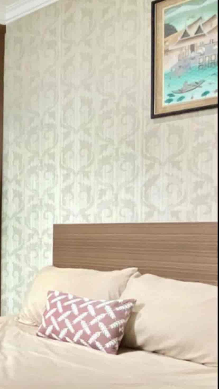 A bedroom with patterned wallpaper behind the bed.