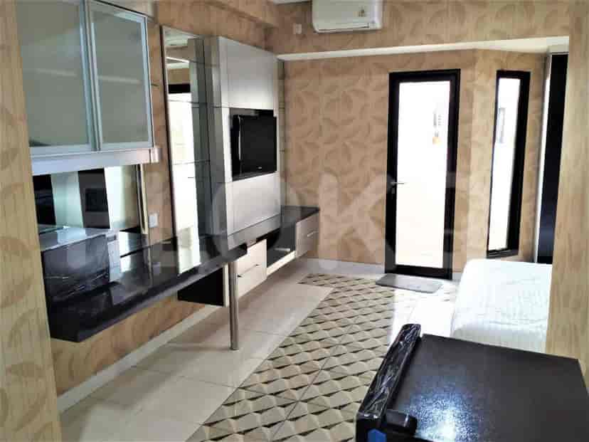 Living room with a TV, desk and a door to the outside.