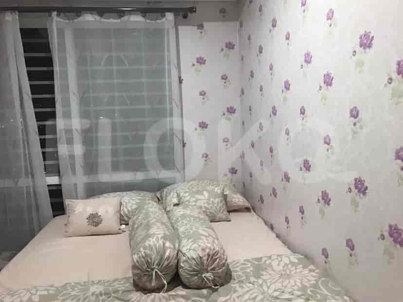 A bedroom with floral wallpaper, bed, and sheer curtains.
